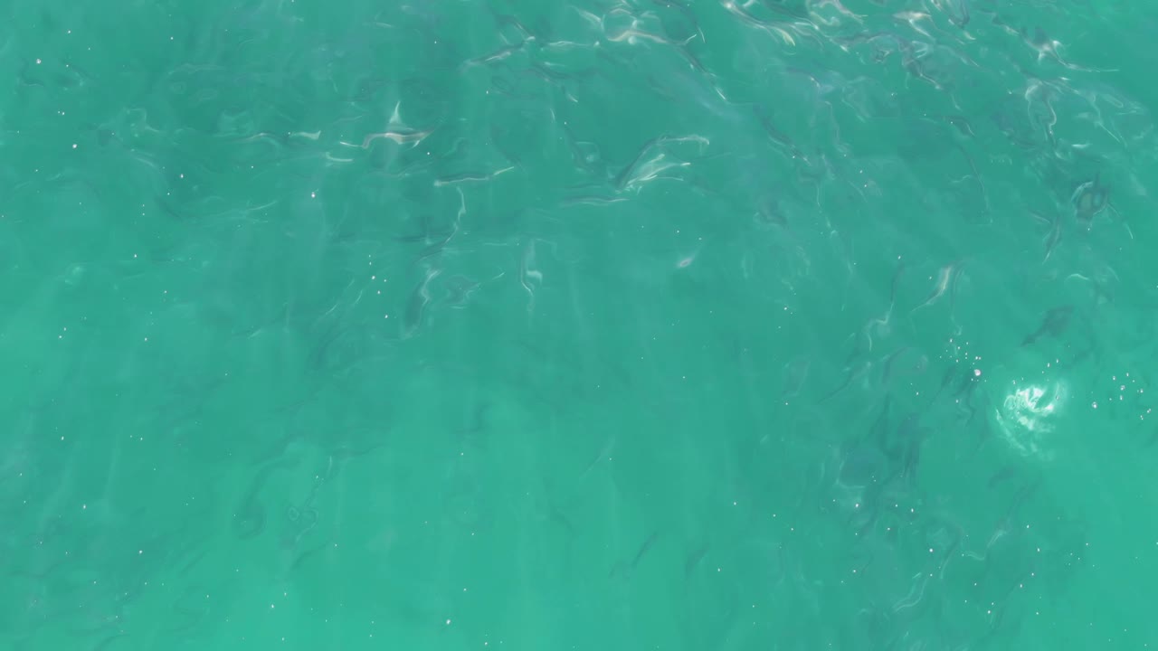 Overhead shallow ocean at Buzzards Beach in Baja California Sur shows more pronounced ripple streaks over turquoise water and no visible people.