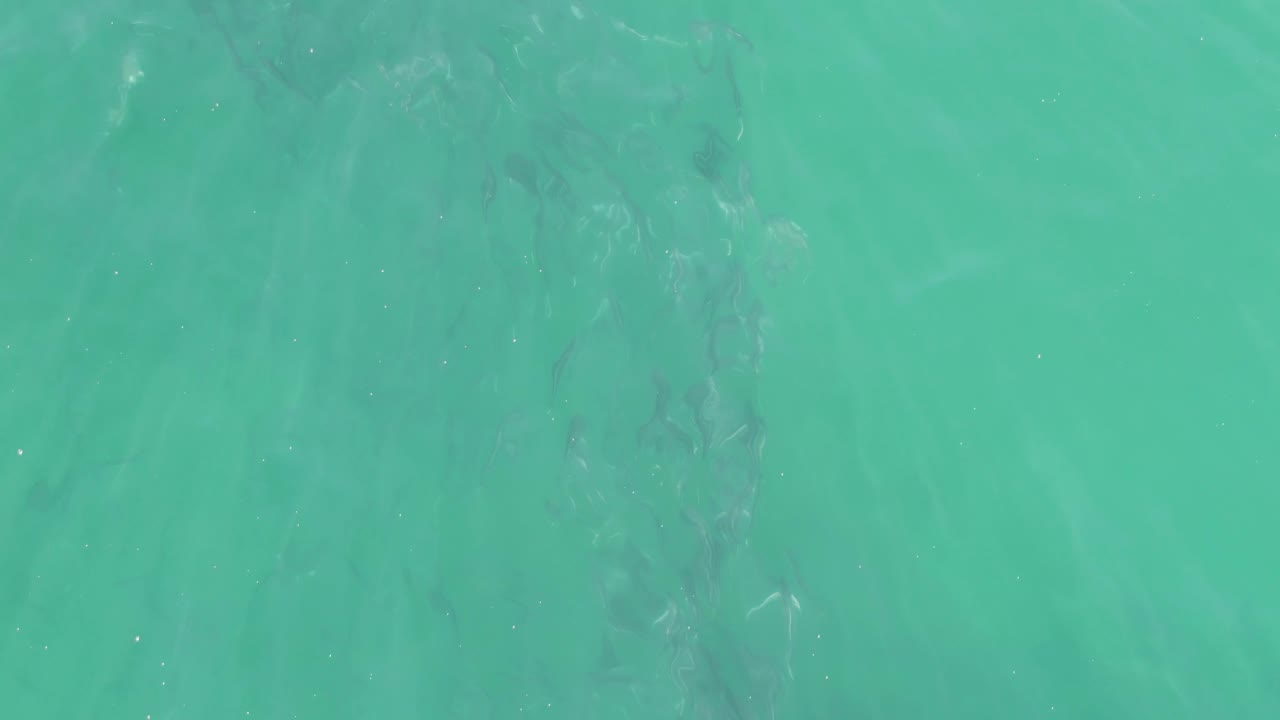 Overhead view of turquoise water at Buzzards Beach, Baja California Sur, with faint submerged streaks near the upper frame and no visible people.