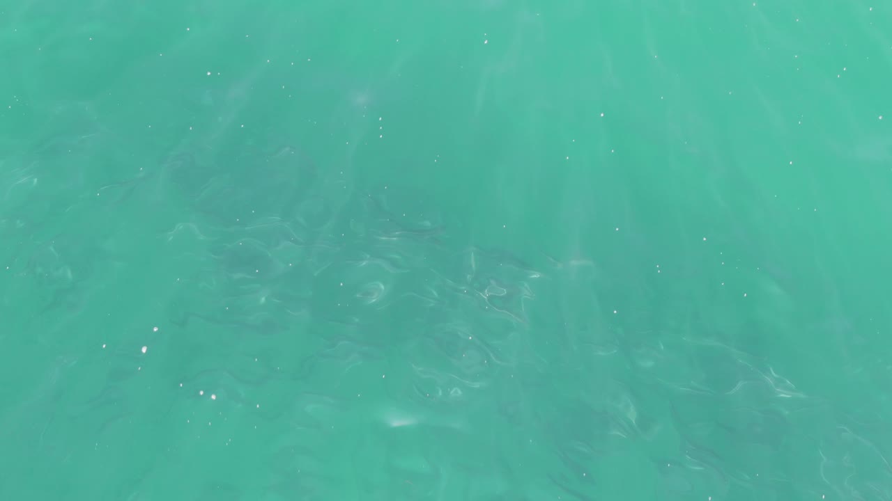 Turquoise ocean water at Buzzards Beach in Baja California Sur, with scattered white bubbles, mild shimmer, and no visible people or objects.