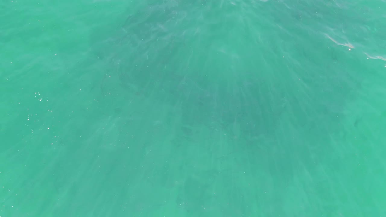 Turquoise shallow water with ripples and pale seabed patterns