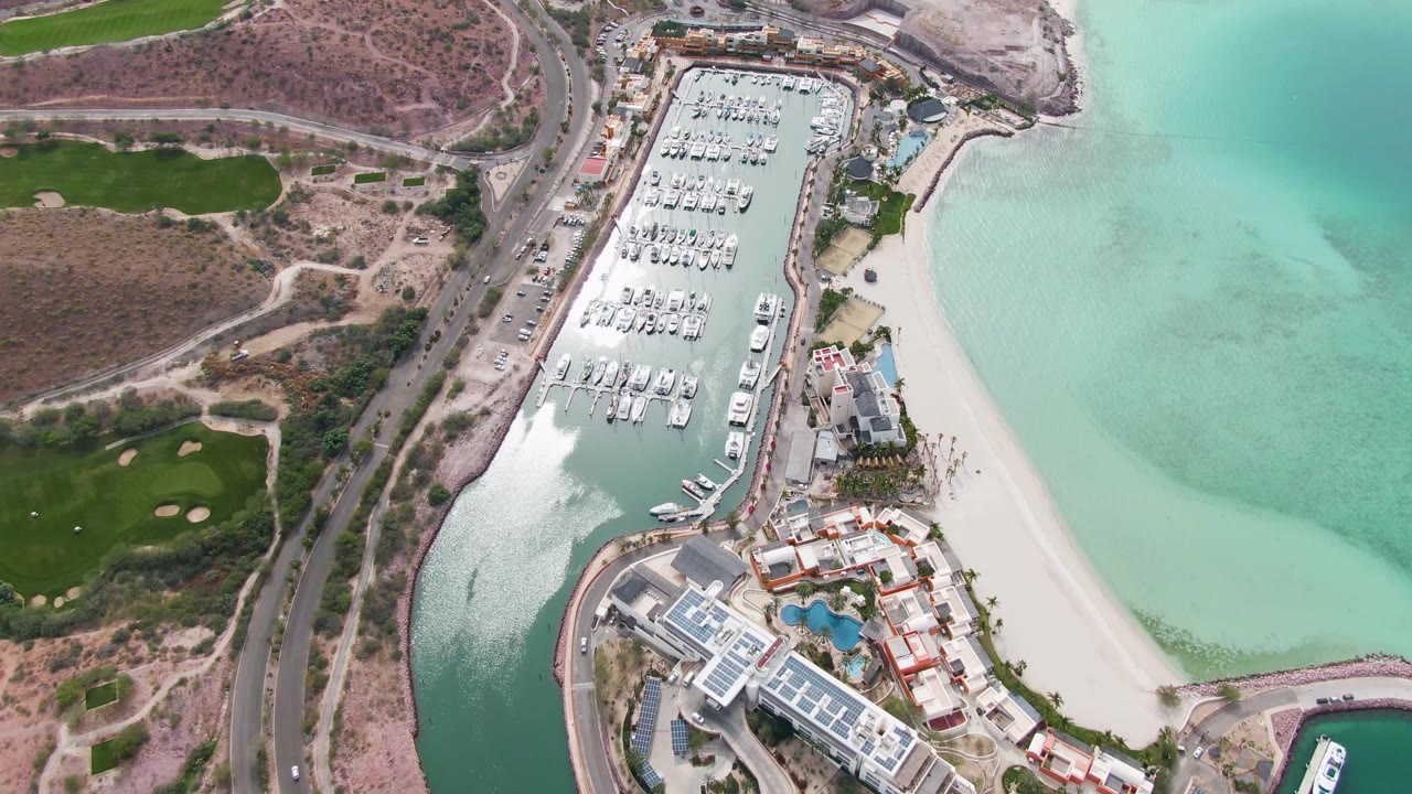 Aerial view of marina docks beside beach and road.