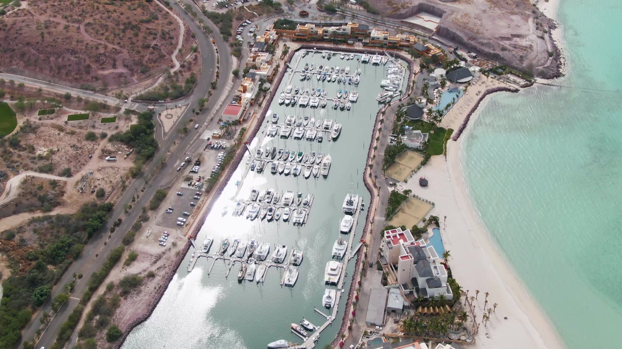 Marina basin with clustered boats beside beach and road traffic