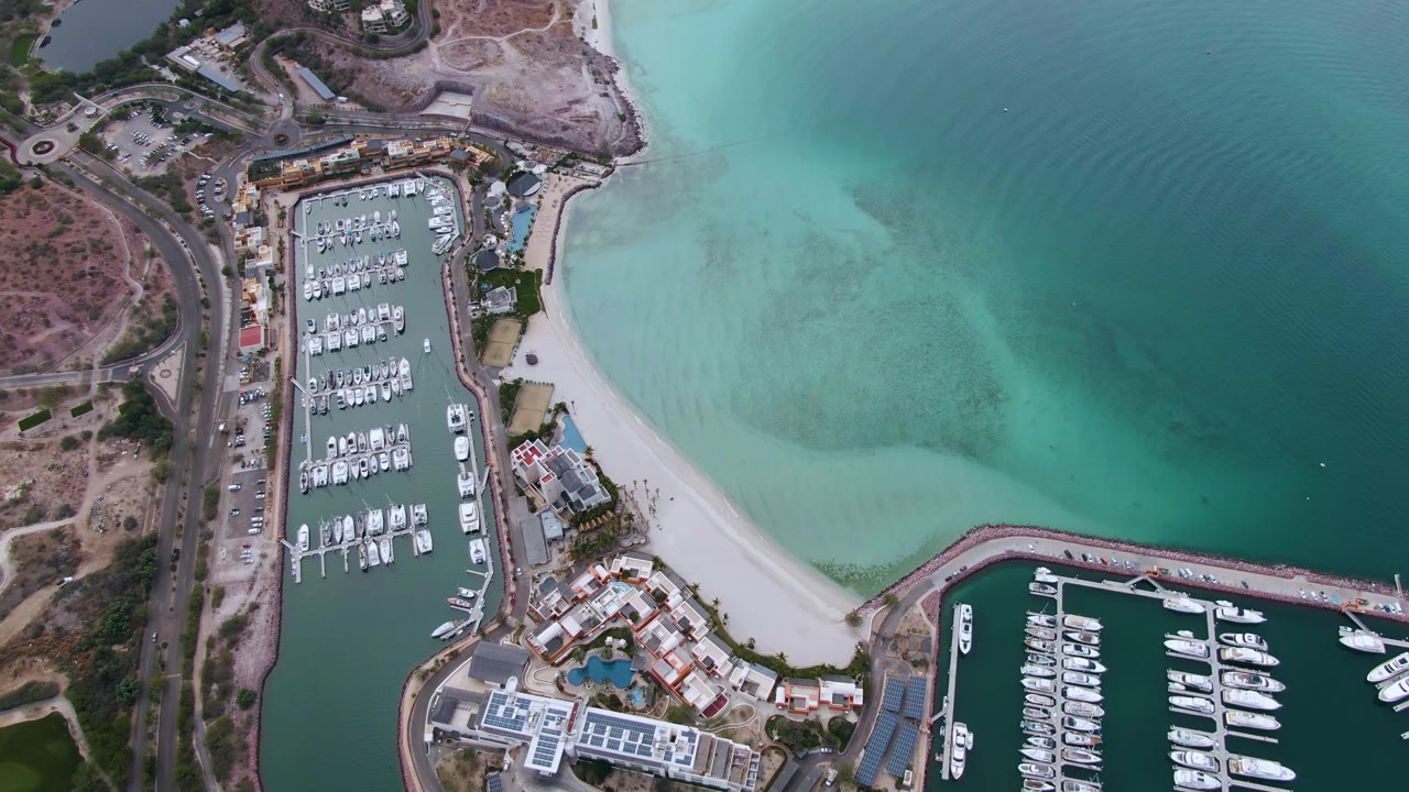 Overhead marina, beach, and turquoise water with docked boats.