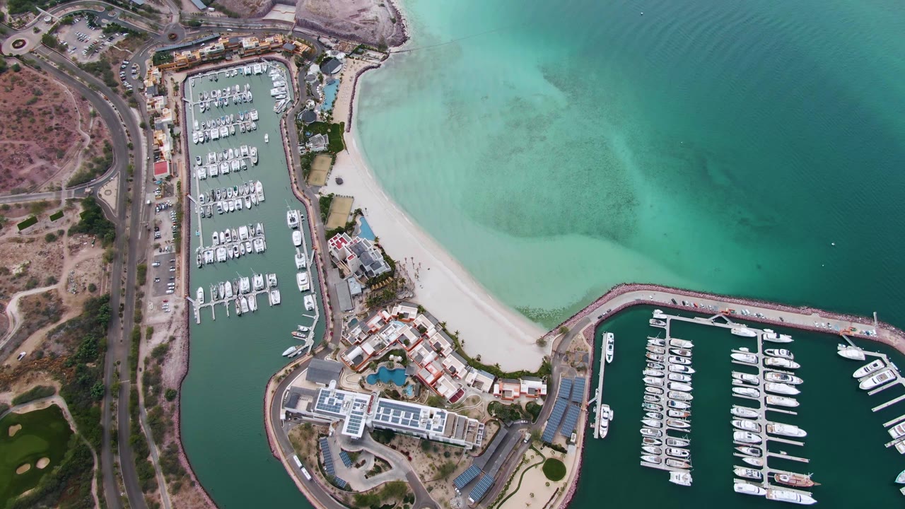 Top-down coastal marina with beach and road.