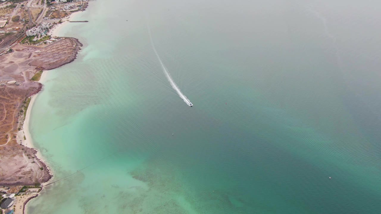 Aerial view in La Paz, Baja California Sur with the boat farther from shore, a narrow wake trailing behind it, and no visible people.