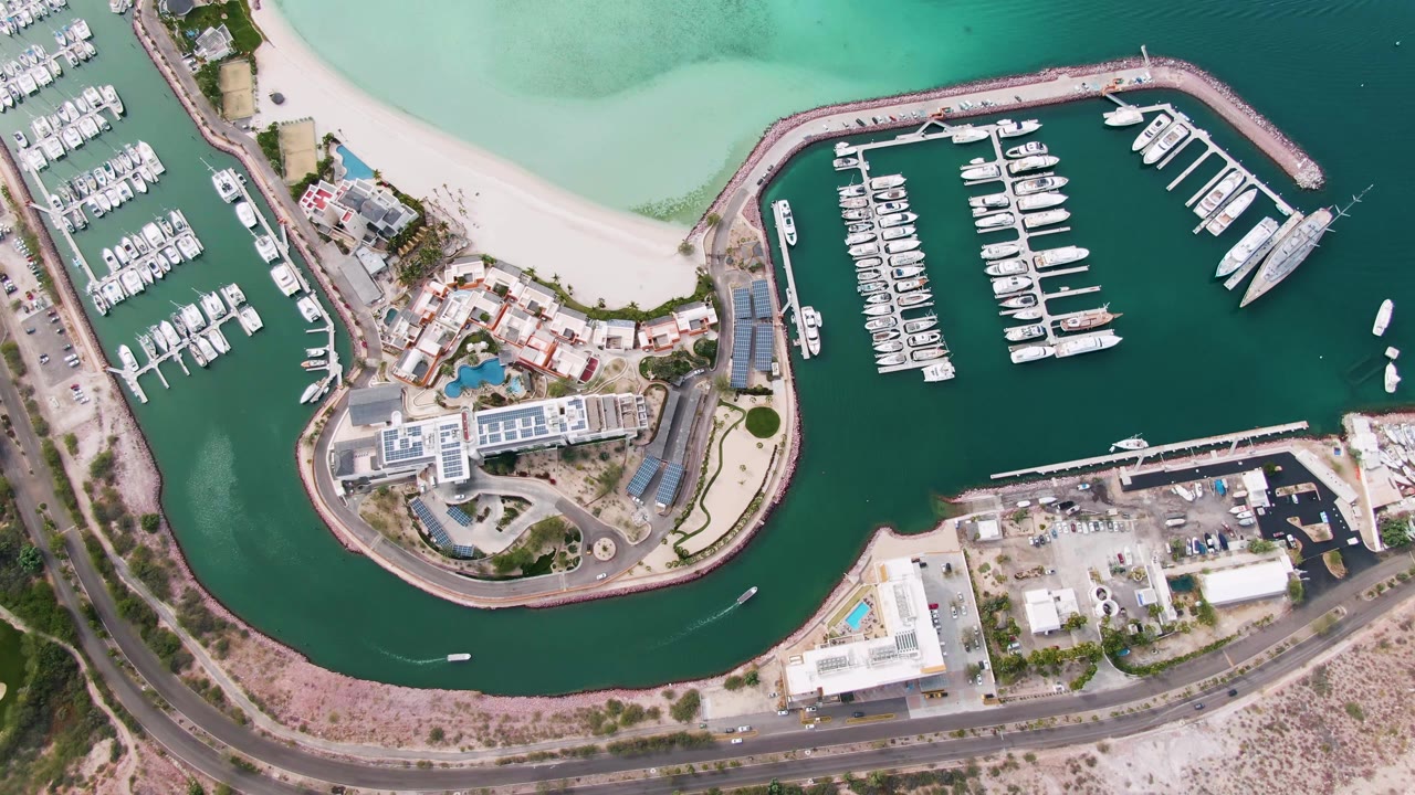 Overhead marina with boats, beach, road, and turquoise water.