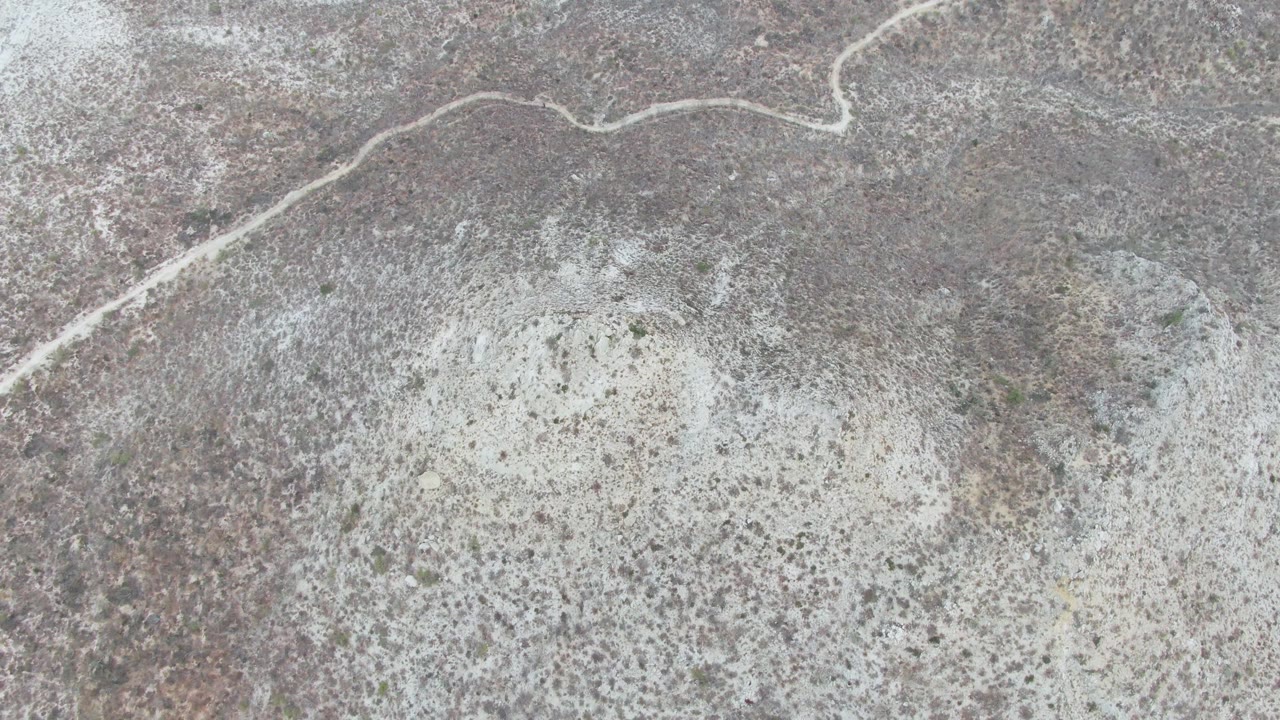 Top-down aerial view of a pale winding road across open arid terrain in Punta Gorda Beach, Baja California Sur, with scattered scrub and no visible people.