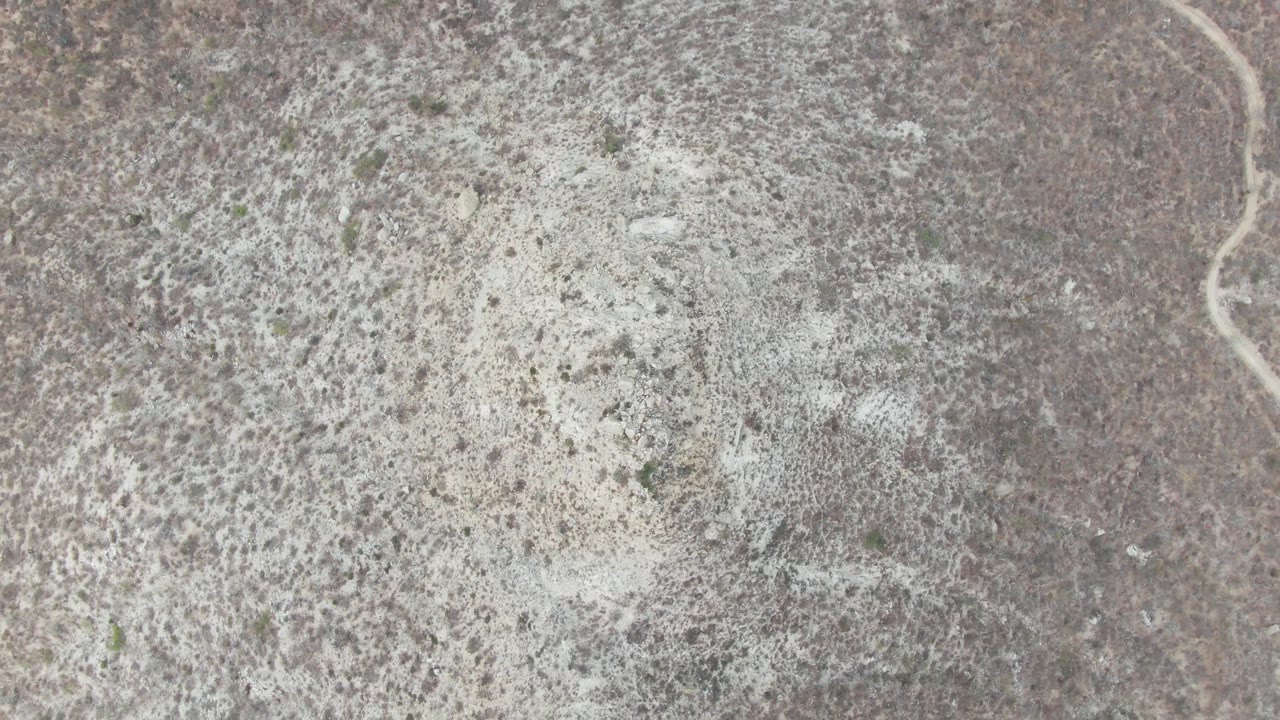 Top-down frame of Punta Gorda Beach area desert terrain with mottled brown vegetation, gray soil, pale sand, and no visible people.