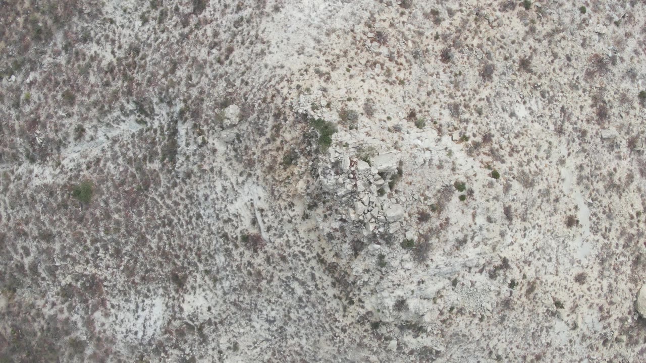Second overhead frame at Punta Gorda Beach showing mottled dry vegetation, pale rocky ground, and no visible people.