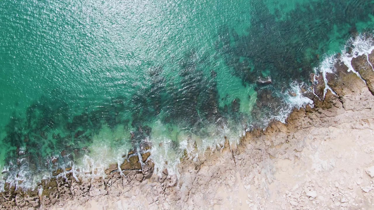 At three seconds, green-blue water has pulled farther from parts of the rocky Punta Gorda Beach shoreline, leaving thin foam streaks and no visible people.