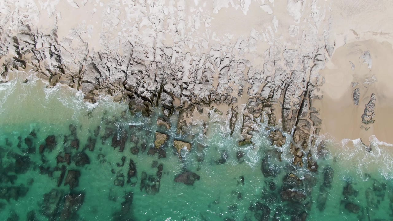 Wave wash thinning over rocks near open sand