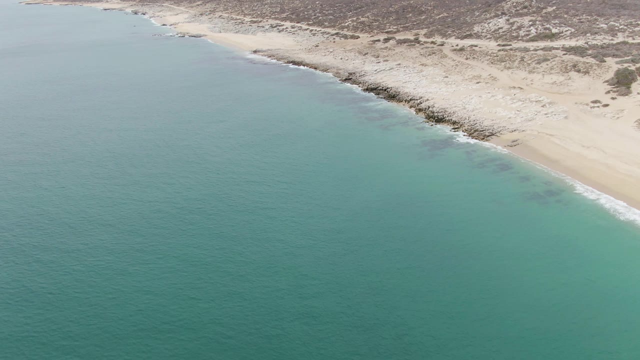 Aerial coastline with broad turquoise water and pale sandy shore