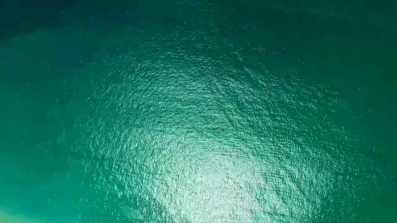 Teal-green ocean water at Marquis Los Cabos fills the frame with a bright reflection low in the image, fine surface ripples, and no visible people.