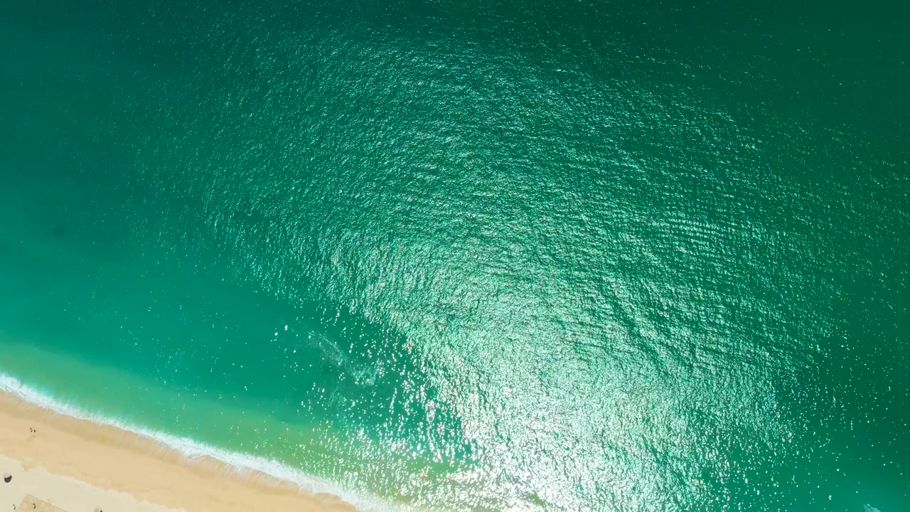 Aerial water texture with foam brushing sandy beach