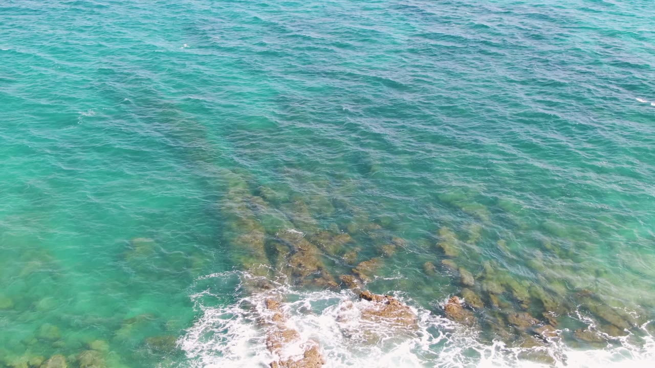 Clear sea water with rocks and small foam patches