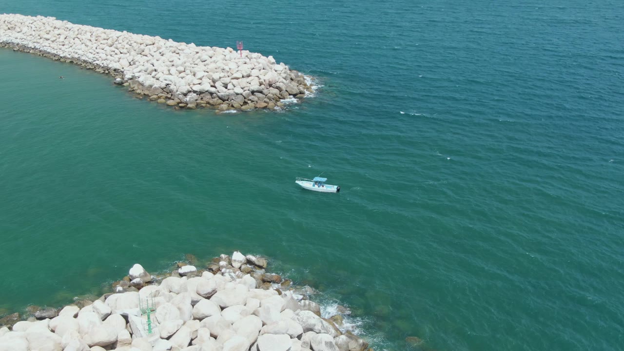 Aerial view of a small boat near rocky coastal structures.