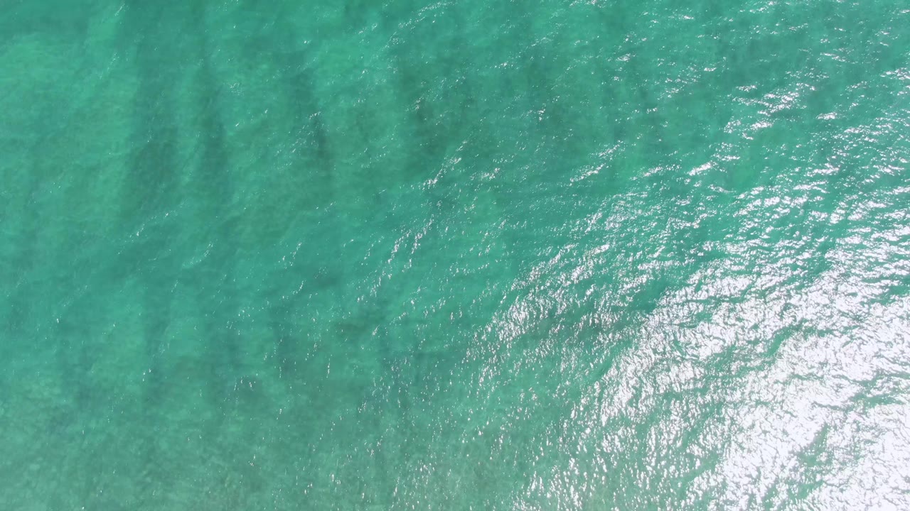 Rippling turquoise ocean with broad sun glare near the lower edge