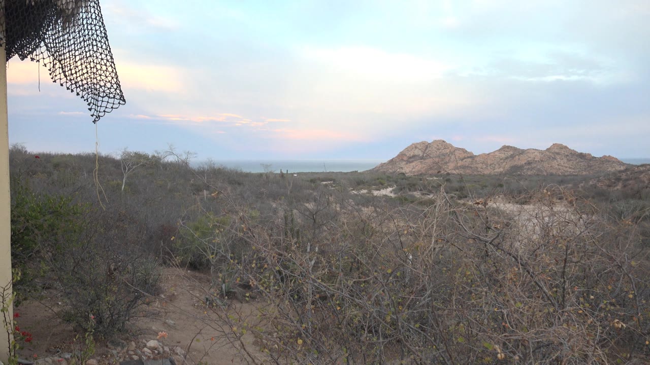Balcony edge beside arid brush and distant desert hills