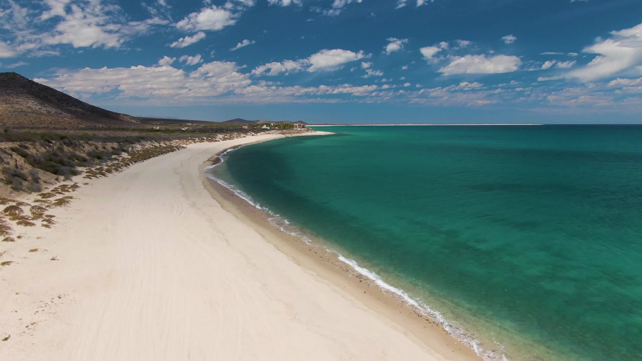 Aerial view of curved white sand beach beside turquoise ocean