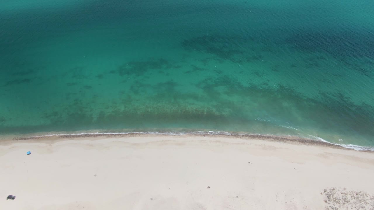 Overhead turquoise water meeting pale sandy beach