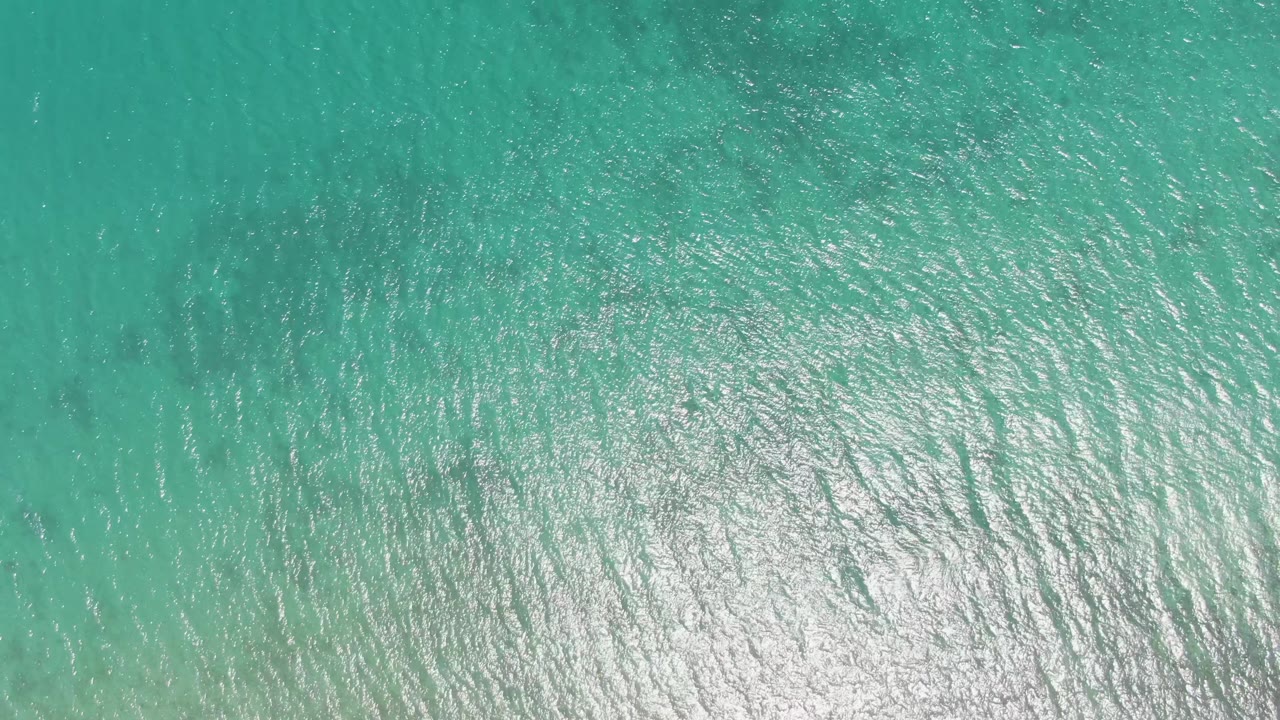 Turquoise sea surface with pale seabed and concentrated shimmer