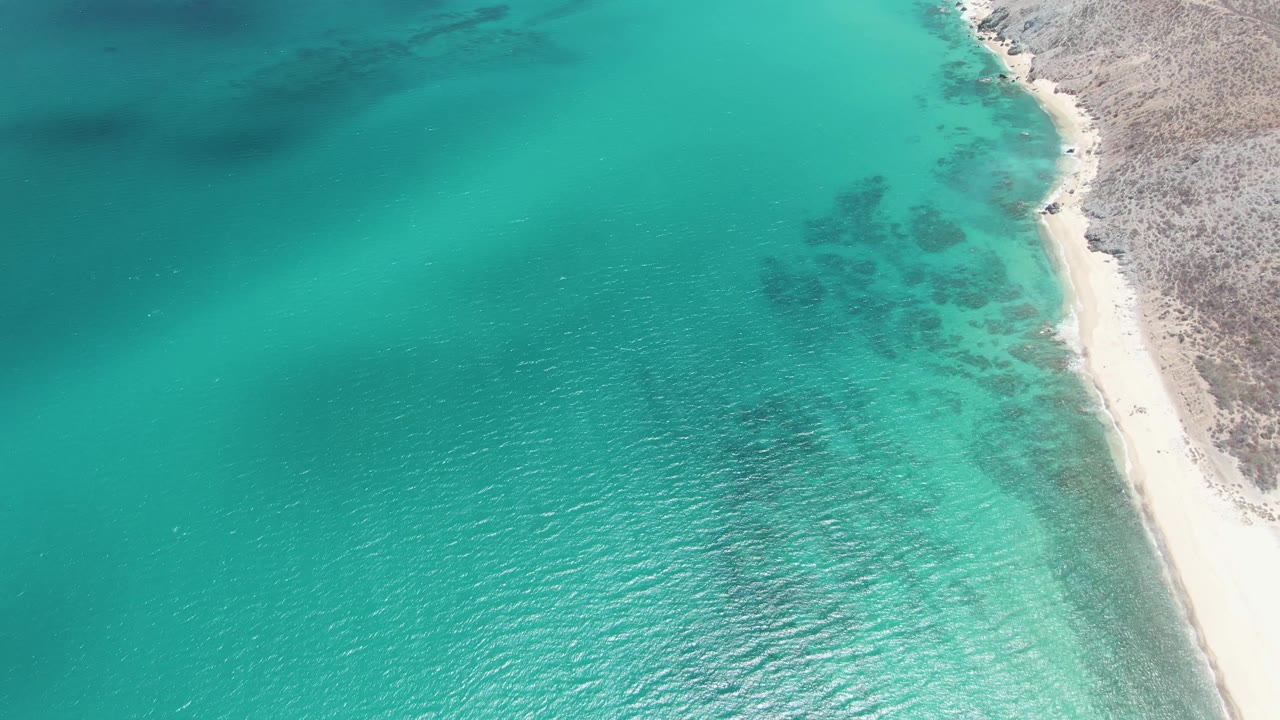 Clear turquoise water and diagonal sandy shoreline from above