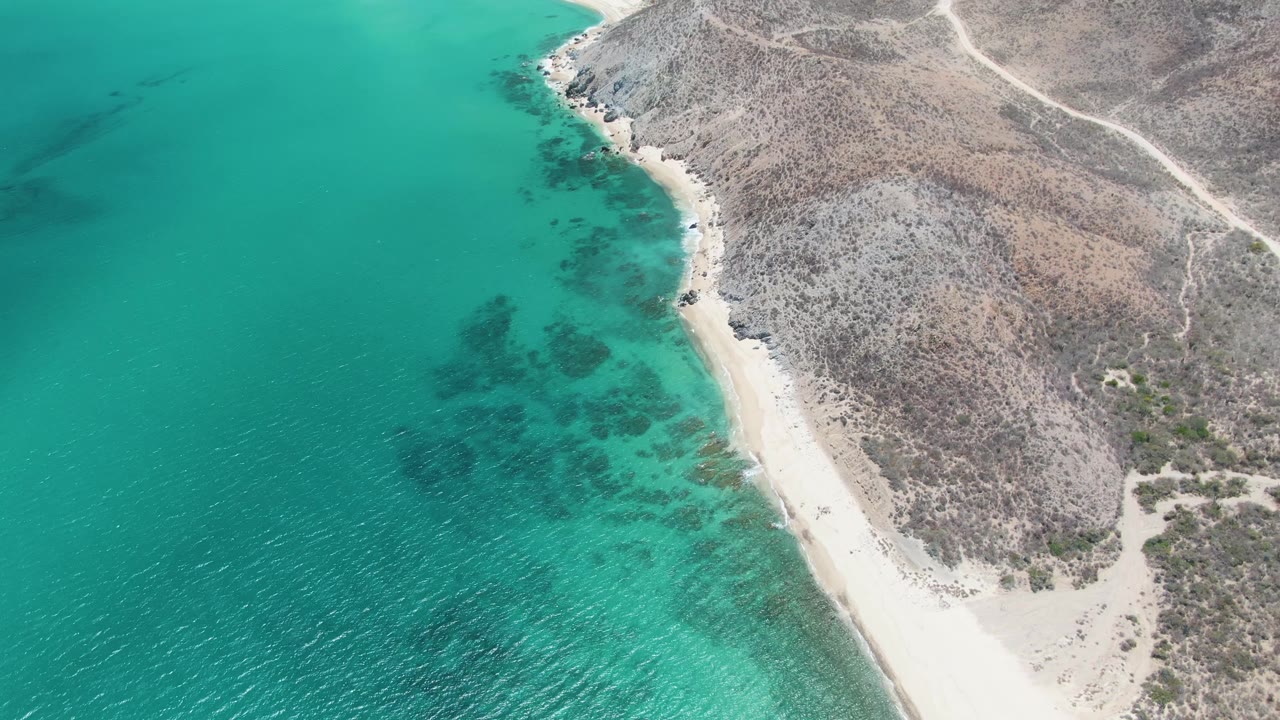Turquoise ocean beside sandy beach and rocky coastal land