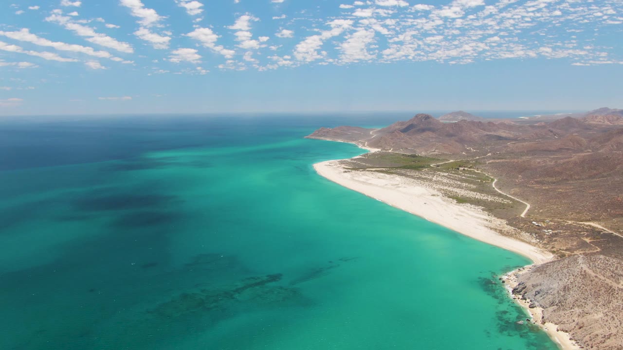 Wide aerial coastline with clear turquoise water and rocky shore.