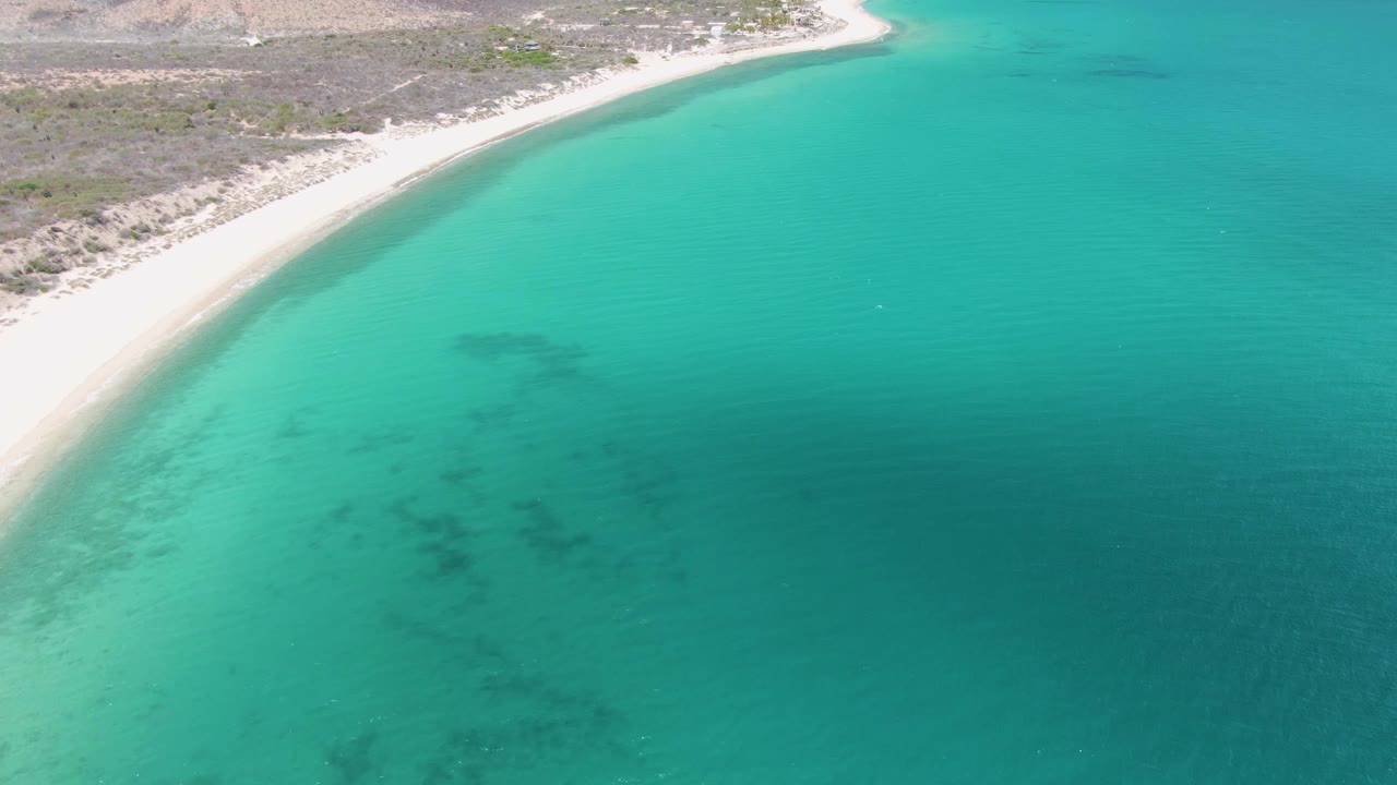 Turquoise coastal water with sandy beach at the upper edge