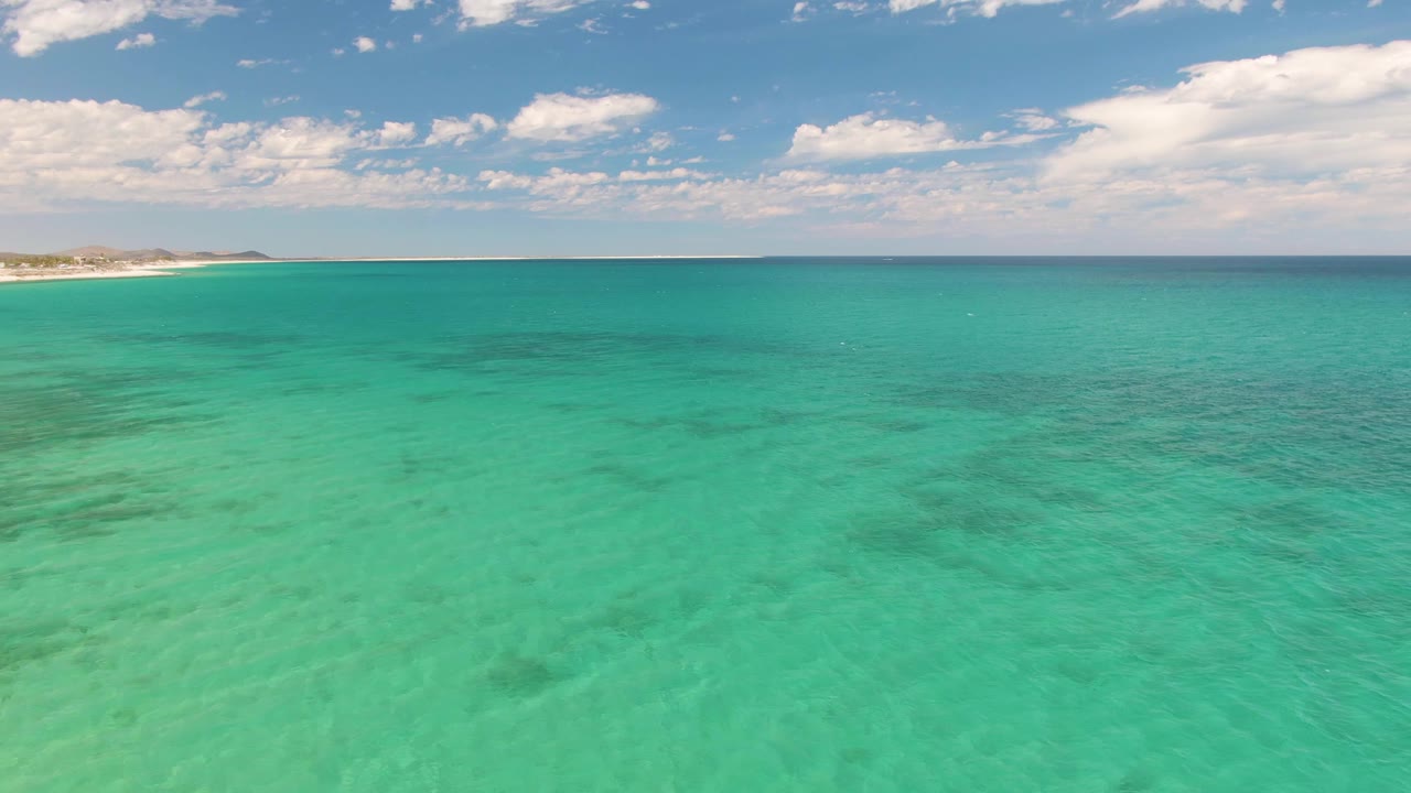 Turquoise ocean with distant shoreline and scattered clouds