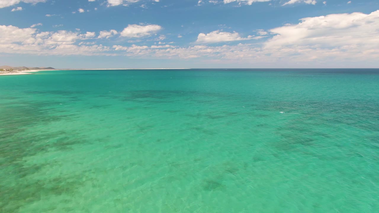 Open turquoise sea at Barakas Beach, Baja California Sur, showing darker patches below the surface, a flat horizon, and no visible people.
