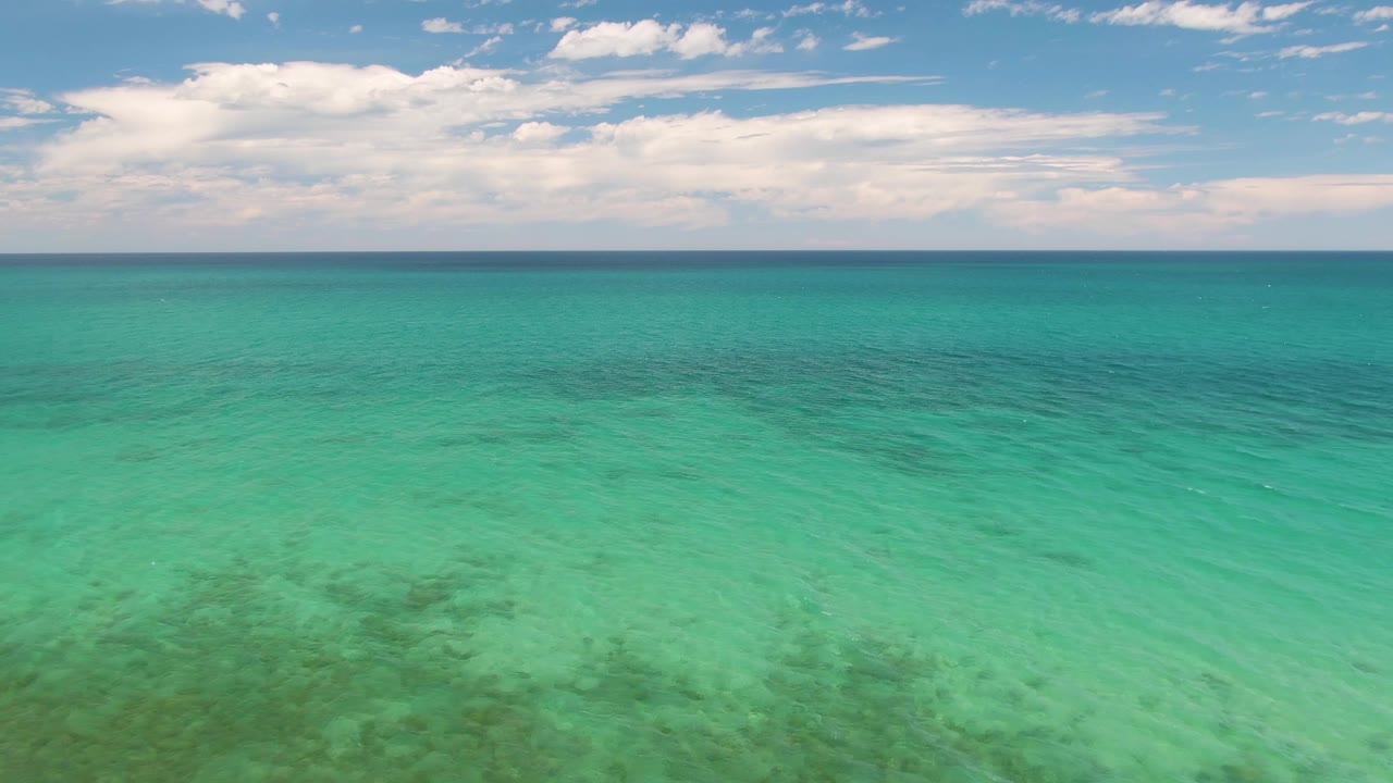 Wide turquoise ocean with a blue horizon and white clouds.
