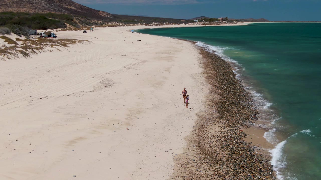 Aerial beach view with two people near a rocky shoreline