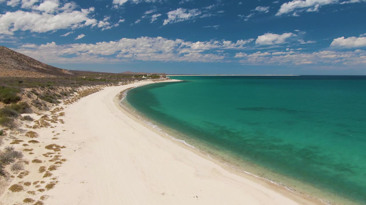 Wide aerial view of empty sand beach and turquoise sea with low surf.