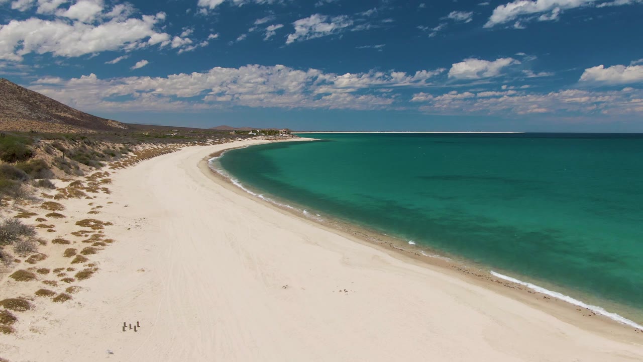 White sand shoreline with turquoise water and small walkers on the beach.