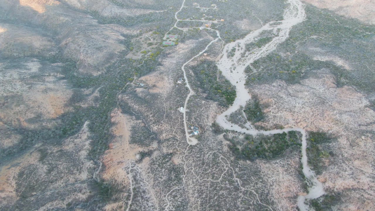 Aerial view of arid hills, dry wash, and a dirt path.