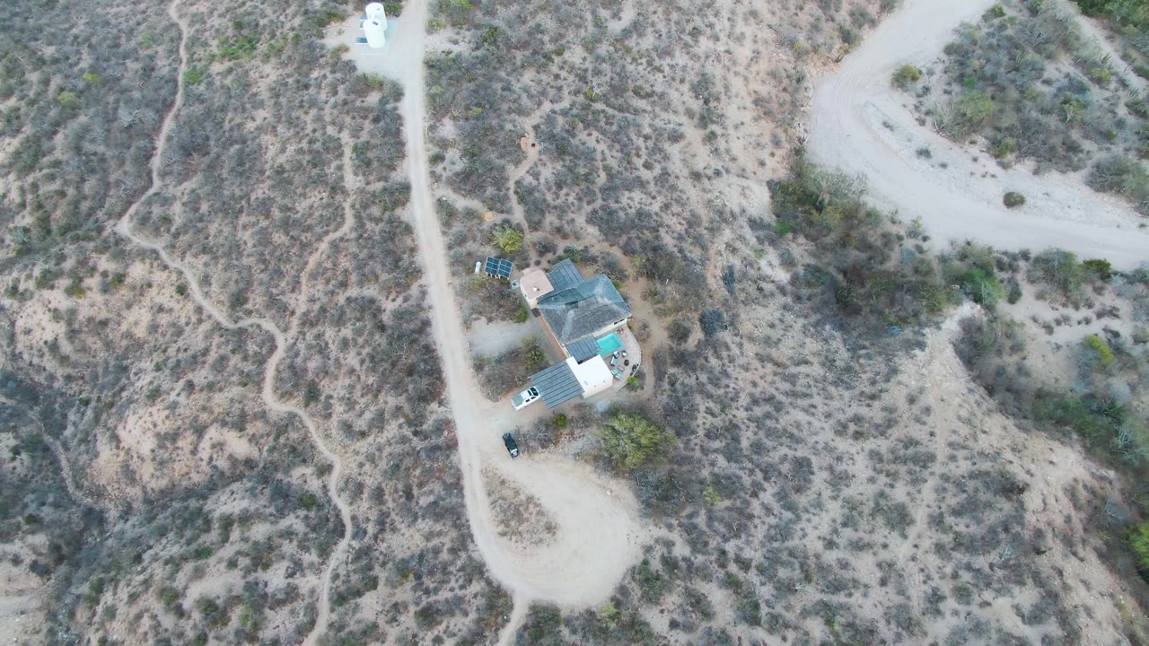 White trailer moving near a house on a dirt road in dry terrain