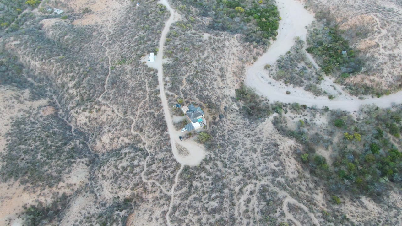 Vehicle farther along a winding dirt road through scrub