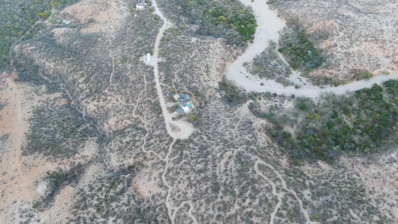 Aerial view of dry terrain crossed by pale dirt tracks.