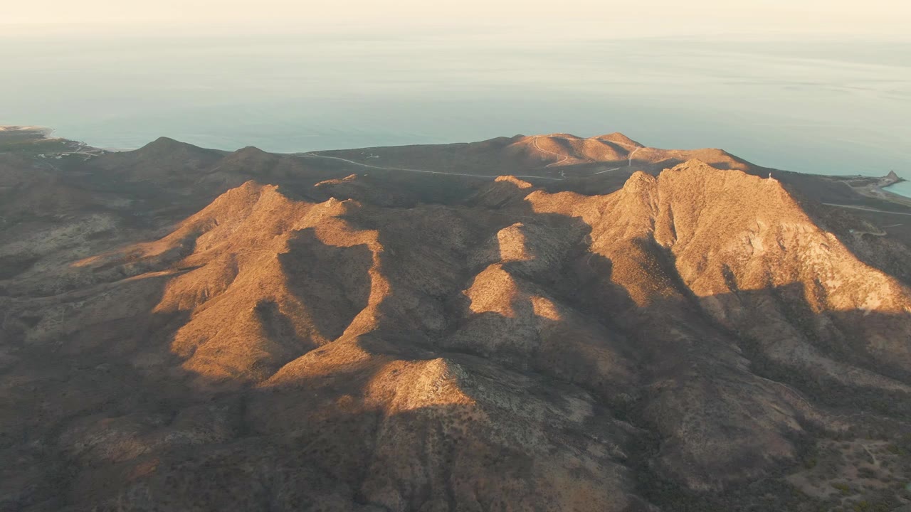 Aerial view of rocky coastal mountains with ocean on the horizon