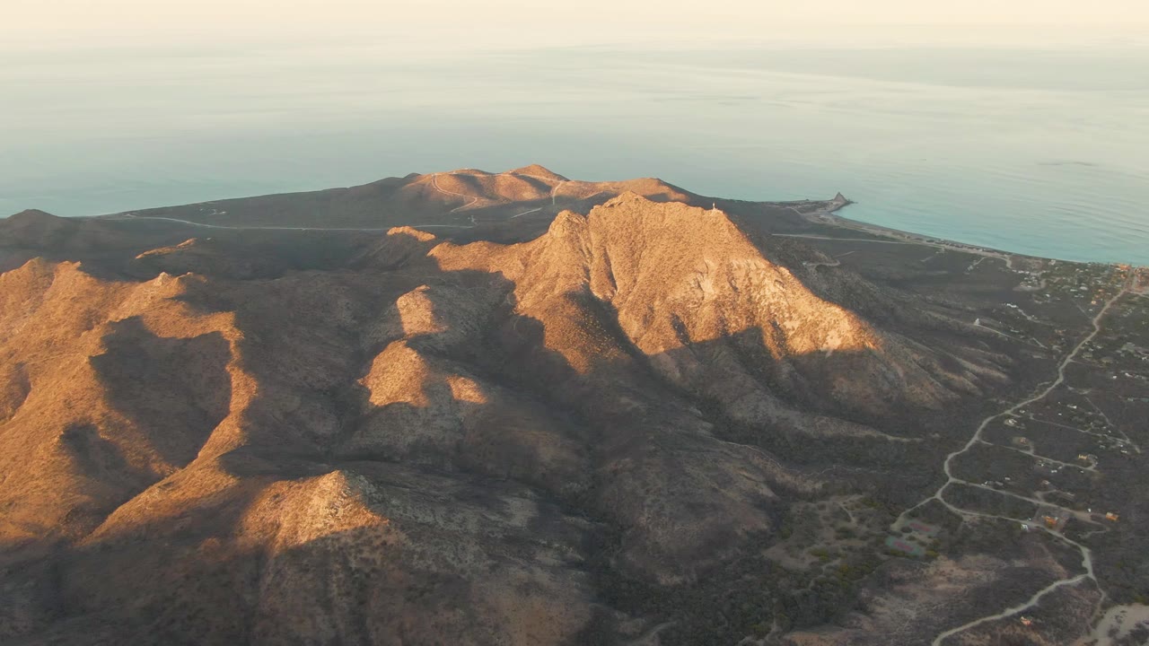 Rocky mountain face with winding coastal roads and ocean background