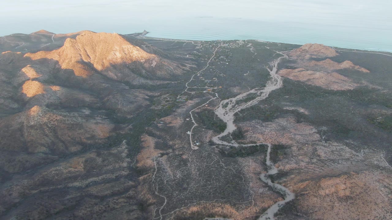 Winding dirt road seen from above in dry mountainous terrain.