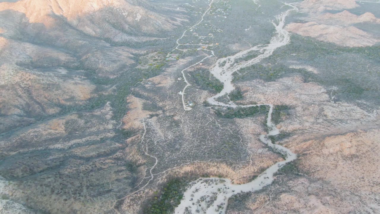 Aerial view of a pale winding riverbed through arid hills