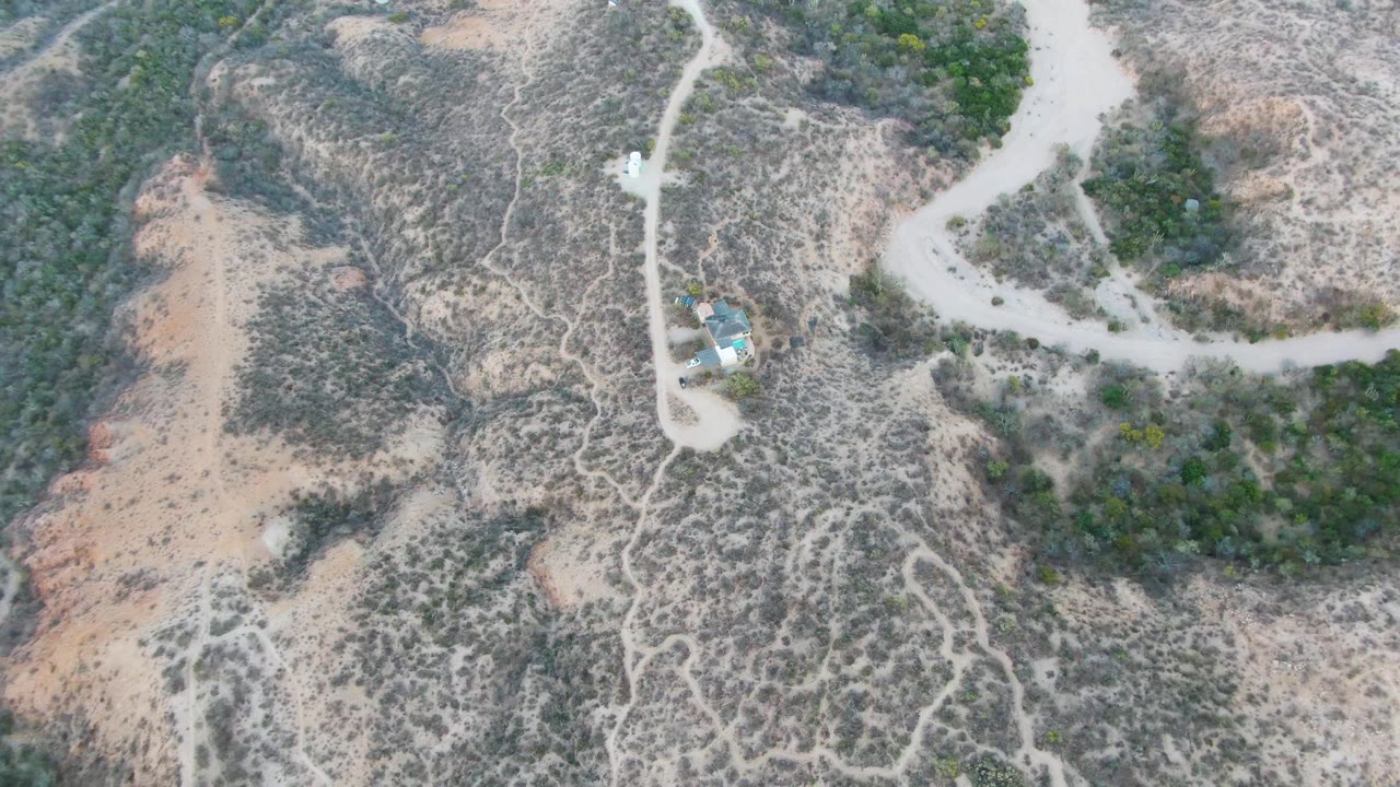 Top-down aerial view of dirt roads beside a small blue-roofed building.