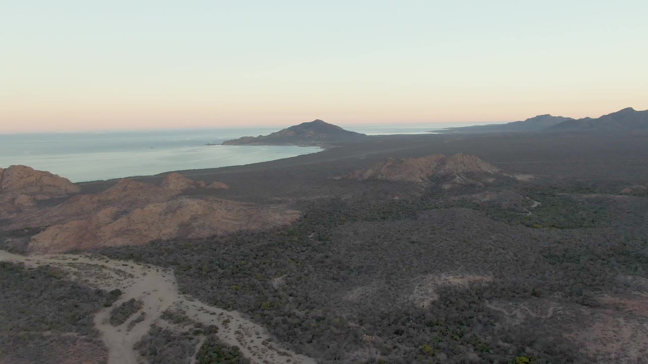 Coastal desert hills and ocean seen from above in soft dusk light
