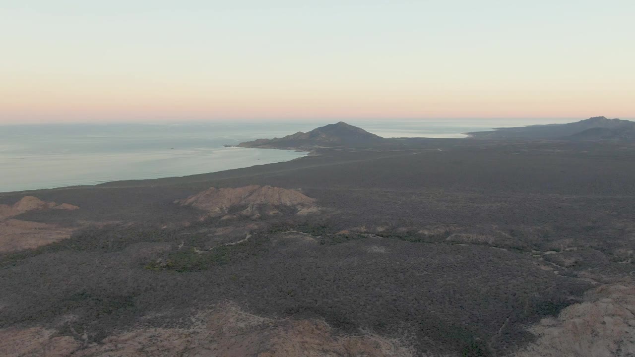 Aerial view of dark volcanic coast and calm ocean at dusk.