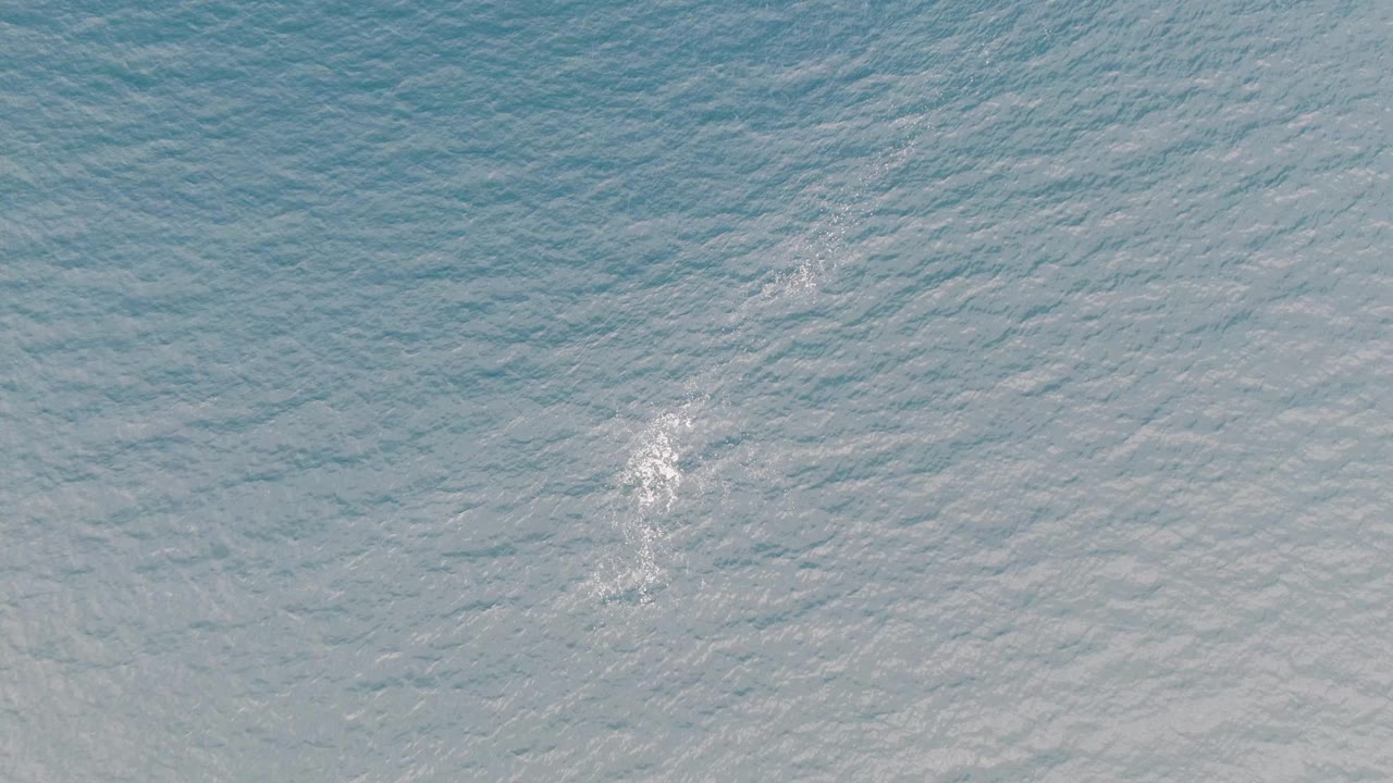 Blue rippled water with white foam near the center