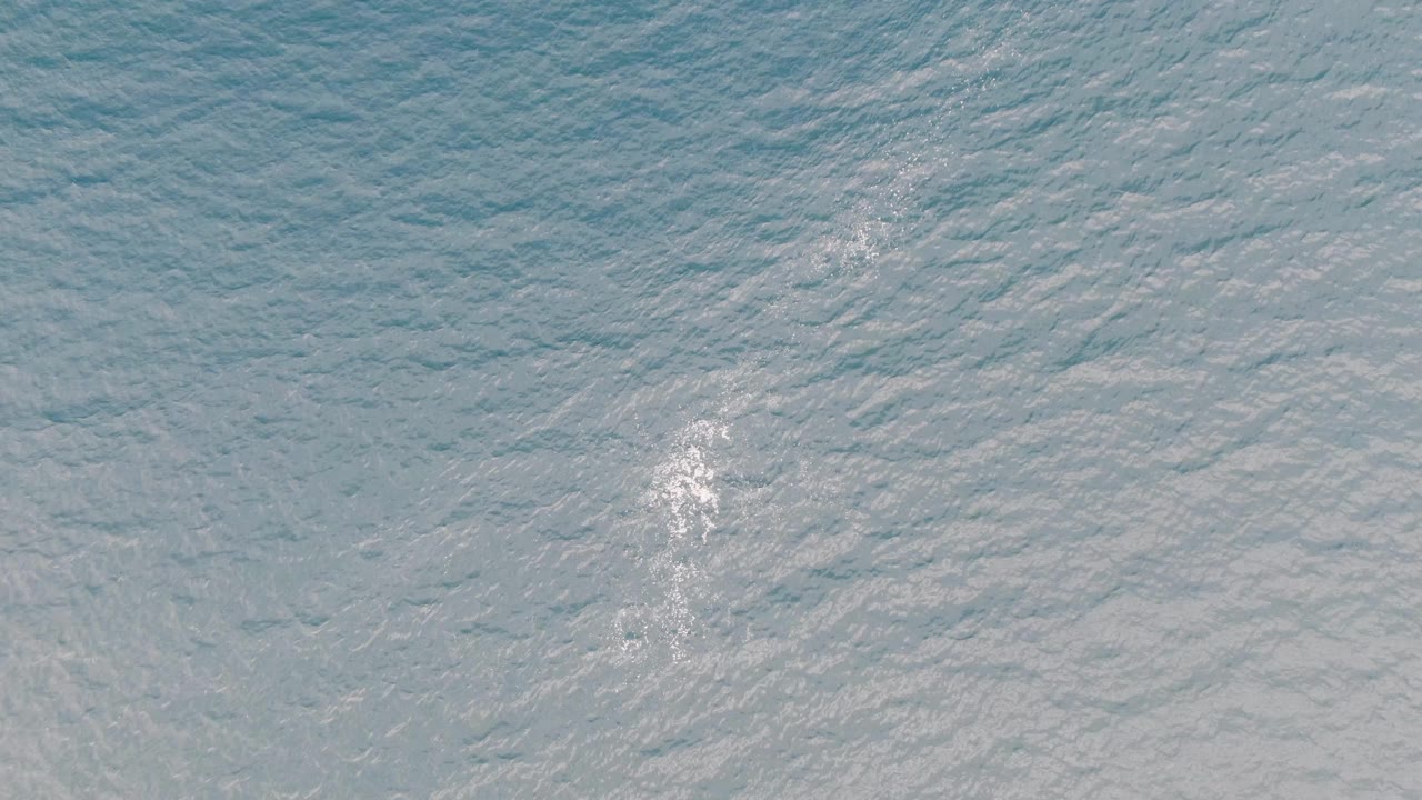 Aerial view of textured ocean water in Baja California Sur with a bright white wake mark near the center-right area and no visible people.