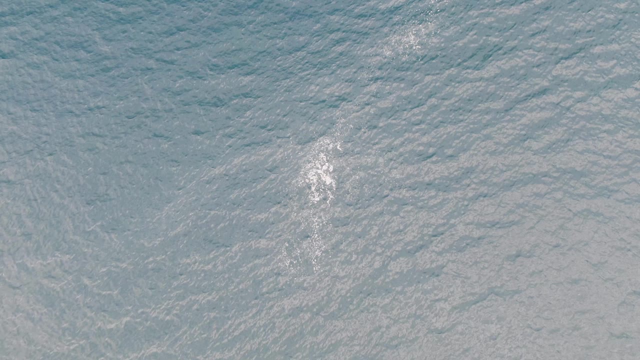 Blue ocean surface from above near Los Barriles, Mexico, with a bright white wake mark against textured ripples and no visible people or shoreline.
