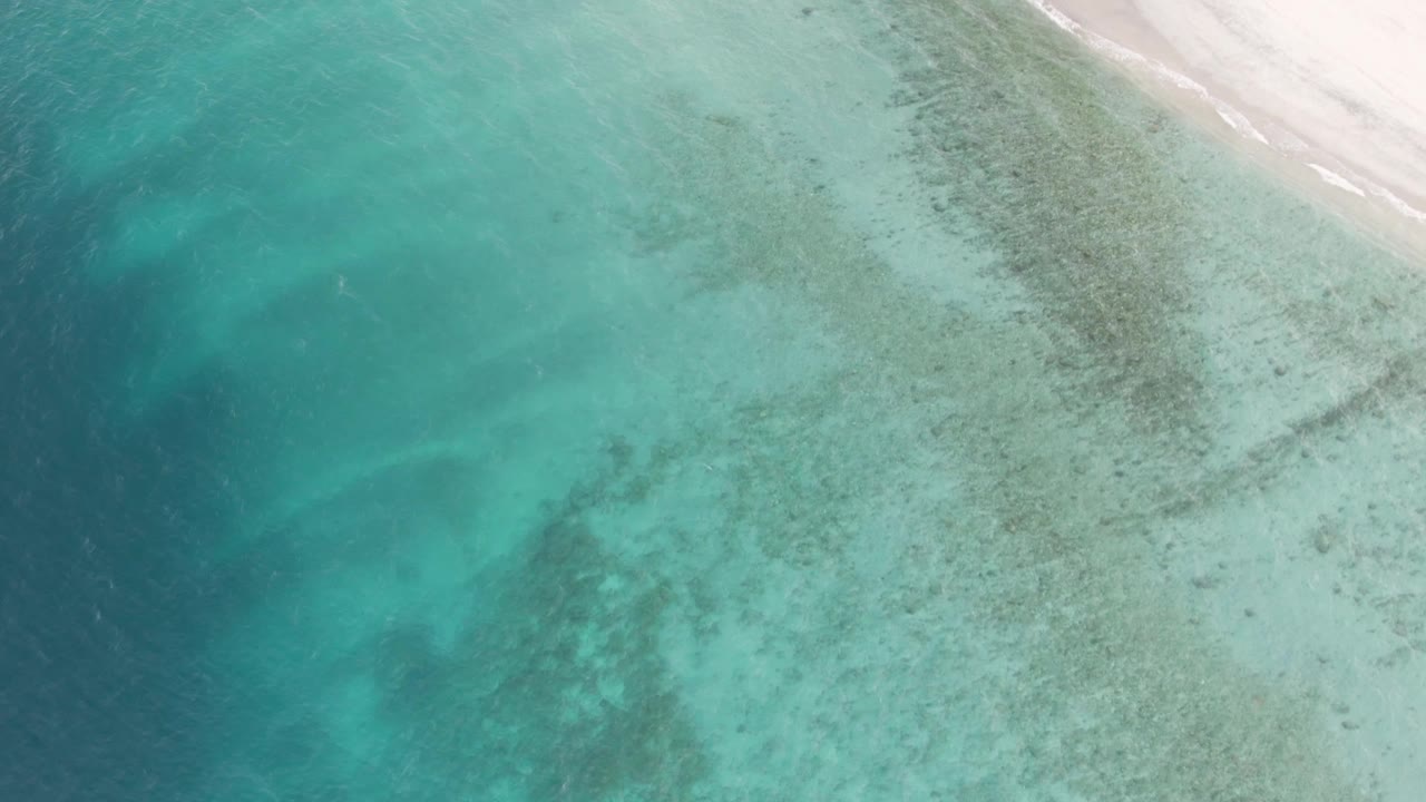 Overhead turquoise water beside a white sand beach